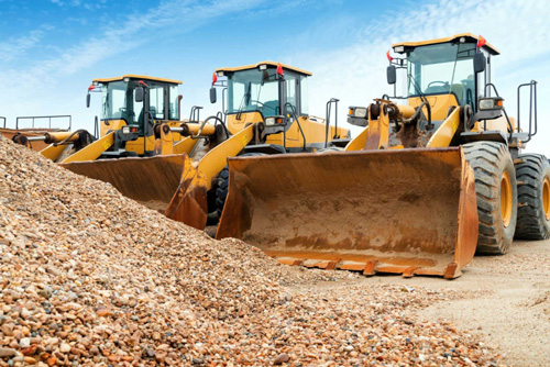 Three large wheel loaders parked near mounds of dirt